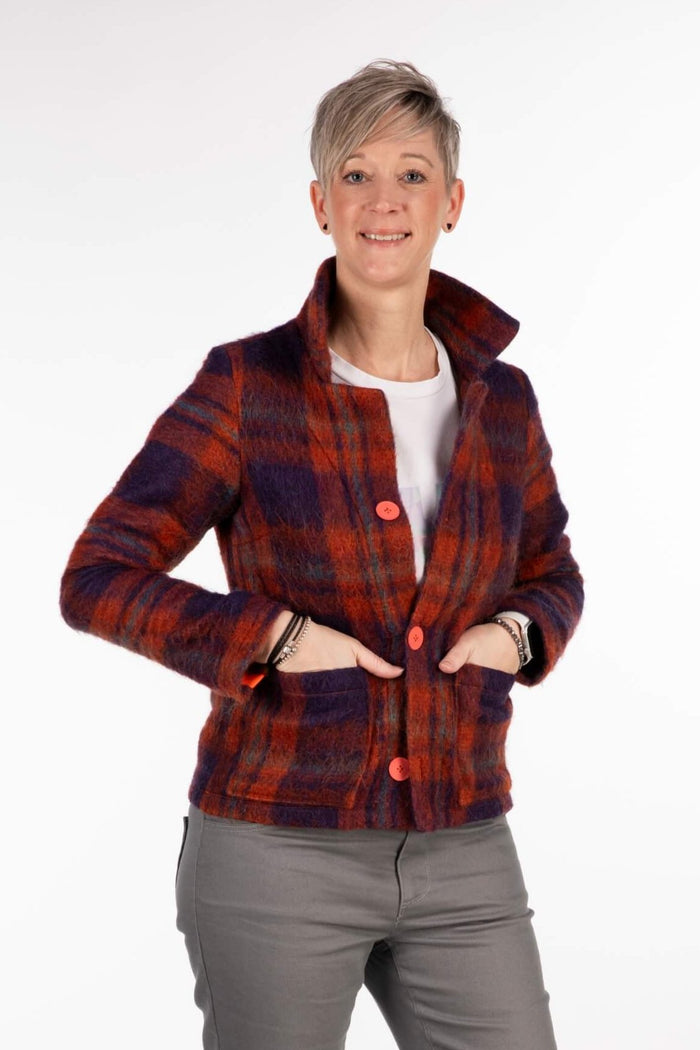 Schräge Frontansicht einer rot und lila karierten Jacke. Model mit den Händen in der Tasche